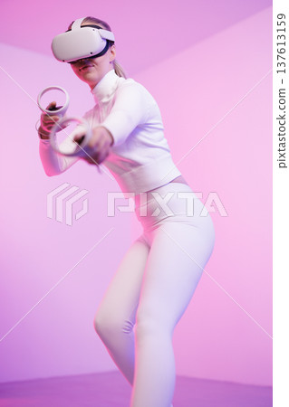 Female in VR glasses practicing martial arts in studio Female in VR glasses practicing martial arts in studio 137613159