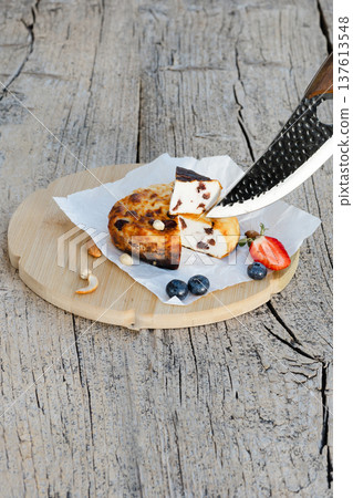Knife cutting cheesecake with berries and nuts on wooden table Knife cutting cheesecake with berries and nuts on wooden table 137613548