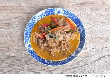 spicy boiled slice beef meat with lemon leaf and eggplant in coconut milk red curry soup on plate 137613572