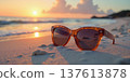 Sunglasses on sandy beach at beautiful orange sunset. 137613878