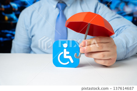 Businessman holds a figurine of a disabled person with a red umbrella. Insurance, safety, inclusion, and financial or social protection. Support for people with disabilities. 137614687