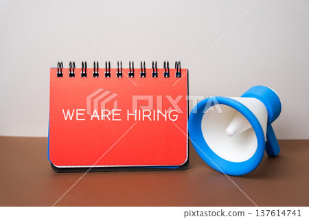 Notebook with the inscription We are hiring in a hand. Employee Search. Attraction to work. 137614741