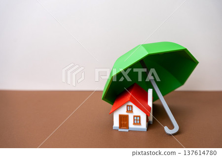 Concept of security and property insurance. Home safety, mortgage protection, real estate investment, family assets. Umbrella and a small house. copy space Concept of security and property insurance. Home safety, mortgage protection, real estate investment, family assets. Umbrella and a small house. copy space 137614780