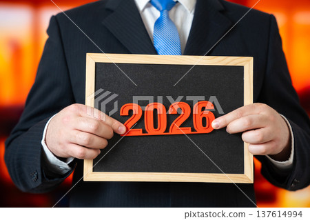 A businessman holds the year 2026 in his hands. New Year in business and commerce. A businessman holds the year 2026 in his hands. New Year in business and commerce. 137614994