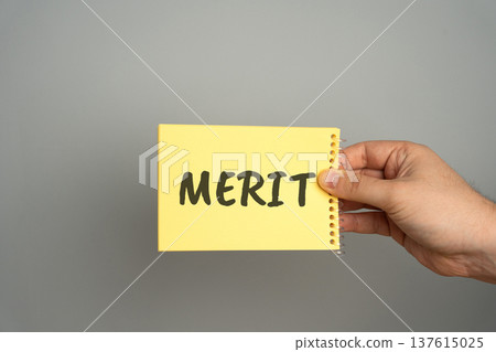 Concept of achievement and recognition. Merit symbolizes success, perseverance, and inner worth a visual metaphor for accomplishment and value. Note in hand with the word Merit Concept of achievement and recognition. Merit symbolizes success, perseverance, and inner worth a visual metaphor for accomplishment and value. Note in hand with the word Merit 137615025