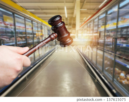 Judges gavel in front of a supermarket grocery counter. Legal regulation, food safety, compliance Judges gavel in front of a supermarket grocery counter. Legal regulation, food safety, compliance 137615075