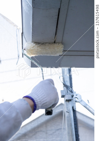 工匠正在用滾筒粉刷房屋外牆的屋簷。 工匠正在用滾筒粉刷房屋外牆的屋簷。 137615498