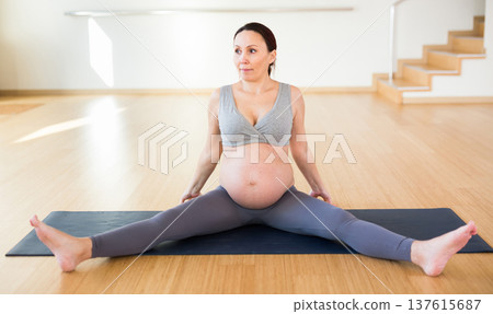 pregnant woman is engaged in yoga. Seated Wide Legged Straddle or Upavistha Konasana pregnant woman is engaged in yoga. Seated Wide Legged Straddle or Upavistha Konasana 137615687