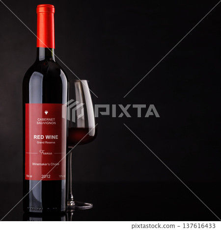 Red wine bottle and glass on dark background 137616433