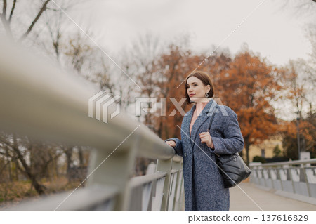 Beautiful young girl stands on an iron bridge near 137616829