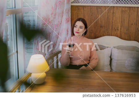 Beautiful young girl sitting at a table in a 137616953