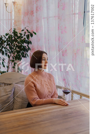Beautiful young girl sitting at a table in a 137617002