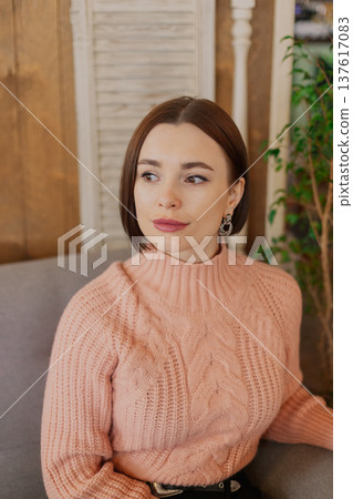 Beautiful young girl sitting at a table in a 137617083