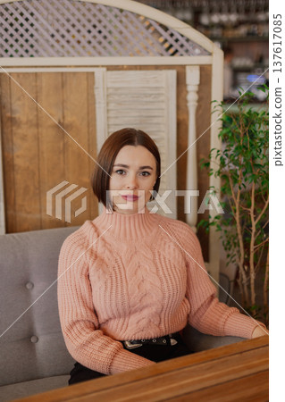 Beautiful young girl sitting at a table in a 137617085