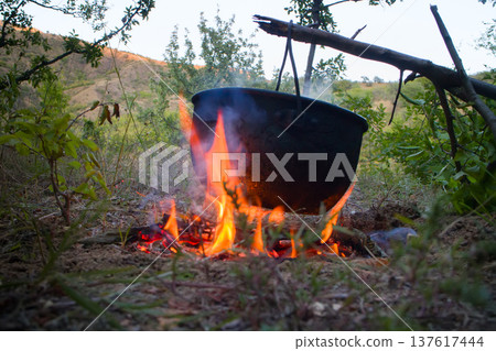 Camp life. On fire to boil pot of soup for traveler Camp life. On fire to boil pot of soup for traveler 137617444