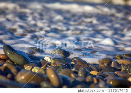 Sea rolling and receding water in rays of setting sun. Sea rolling and receding water in rays of setting sun. 137617445