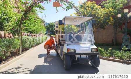 A farmer repairs a wheel on his mini-electric truck, combining modern technology with traditional farming A farmer repairs a wheel on his mini-electric truck, combining modern technology with traditional farming 137617630