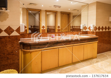 A spacious restroom with elegant brown tiled walls and floors creating a warm and cozy atmosphere for relaxation and comfort A spacious restroom with elegant brown tiled walls and floors creating a warm and cozy atmosphere for relaxation and comfort 137617634