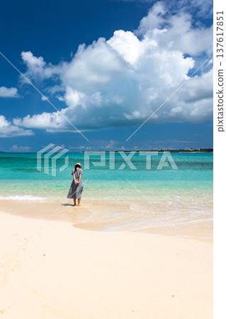 A woman looking at the blue sea and a tropical beach scene A woman looking at the blue sea and a tropical beach scene 137617851