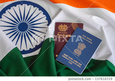 View of Overseas Citizen of India Card with Portuguese passport on Indian flag background. View of Overseas Citizen of India Card with Portuguese passport on Indian flag background. 137618729