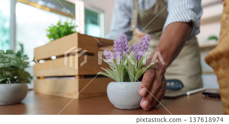 Sustainability in Action: A gardener arranging a potted plant on a table Sustainability in Action: A gardener arranging a potted plant on a table 137618974