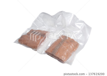 two slices of frozen salmon, closed in a plastic bag two slices of frozen salmon, closed in a plastic bag 137619200