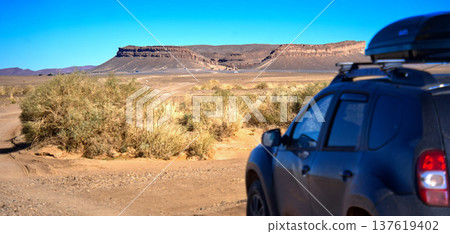 Suv traveling desert landscape towards gara medouar in morocco Suv traveling desert landscape towards gara medouar in morocco 137619402