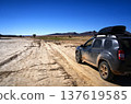Suv driving on remote dirt track in arid landscape 137619585