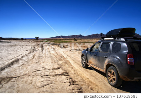 Suv driving on remote dirt track in arid landscape Suv driving on remote dirt track in arid landscape 137619585
