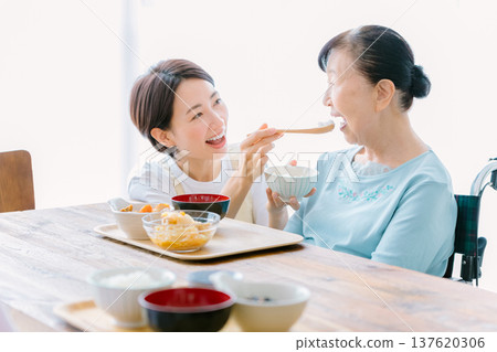 Senior woman having a meal with a caregiver 137620306