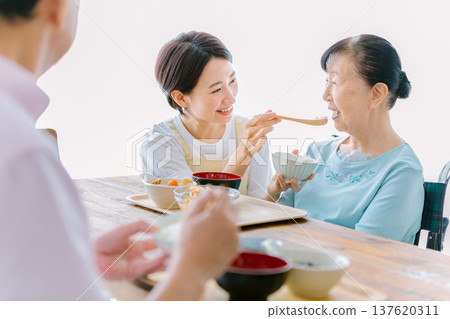 Senior couple having a meal with a caregiver 137620311