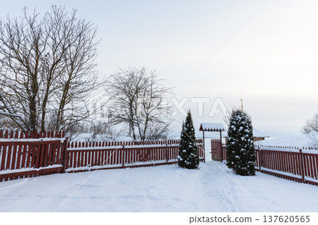 A snowy winter scene, red wooden fence and open gate A snowy winter scene, red wooden fence and open gate 137620565
