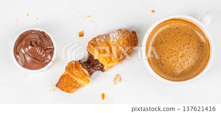 Broken chocolate croissant with coffee and spread top view 137621416