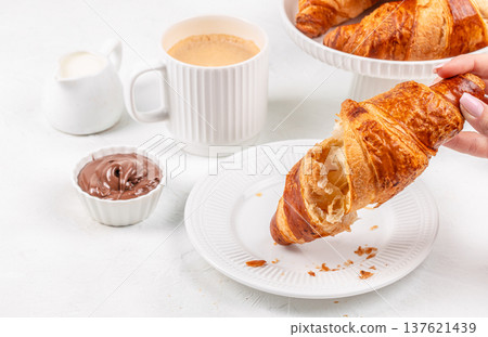 Woman holding croissant with chocolate spread and coffee breakfast Woman holding croissant with chocolate spread and coffee breakfast 137621439