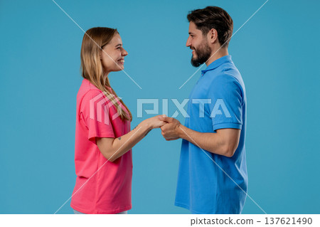 Love confession. Happy couple stands on blue, holding hands, look into eyes. Romantic feelings, perfect relationships. 137621490