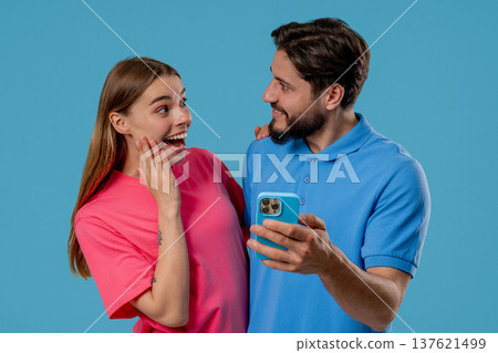 Young Couple Using Mobile Device. Woman Man Watching, Laughing With Smartphone Young Couple Using Mobile Device. Woman Man Watching, Laughing With Smartphone 137621499