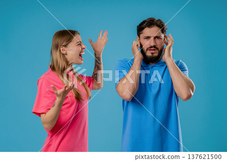 Grumpy Woman Quarrels On Husband Or Boyfriend On Blue. Tired Man Shut His Ears Grumpy Woman Quarrels On Husband Or Boyfriend On Blue. Tired Man Shut His Ears 137621500