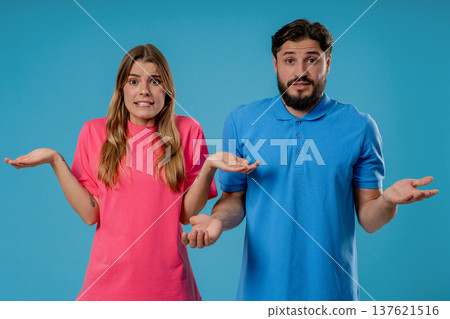 Confused young couple shrugging shoulders in uncertainty while looking at camera Confused young couple shrugging shoulders in uncertainty while looking at camera 137621516