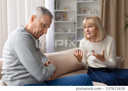 Senior couple experiencing relationship conflict while talking on sofa at home Senior couple experiencing relationship conflict while talking on sofa at home 137621630