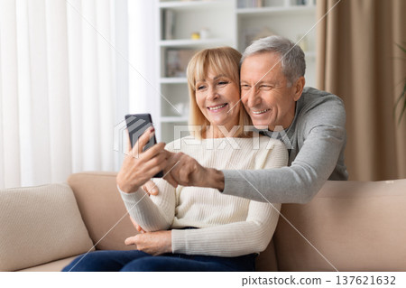 Happy senior couple sitting on sofa at home taking selfie with smartphone 137621632
