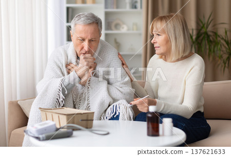 Senior man sitting wrapped in blanket while coughing during illness at home 137621633
