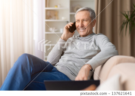 Happy senior man sitting comfortably on sofa at home talking on smartphone 137621641