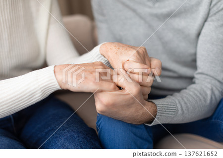 Closeup of senior couple holding hands in comforting gesture at home Closeup of senior couple holding hands in comforting gesture at home 137621652
