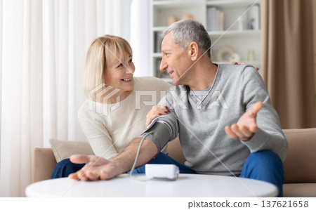 Senior couple measuring blood pressure at home and discussing the results Senior couple measuring blood pressure at home and discussing the results 137621658