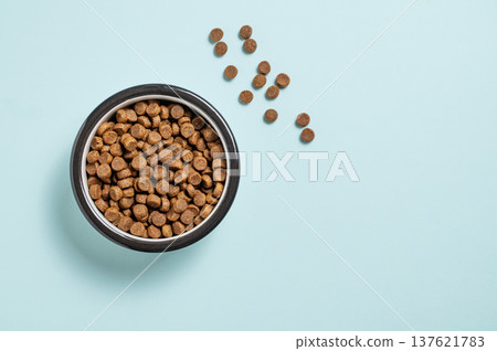 A bowl of dry dog food on a isolated blue background. A bowl of dry dog food on a isolated blue background. 137621783