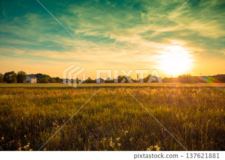 Rural landscape with beautiful gradient evening sky at sunset. Green field and village on the horizon 137621881