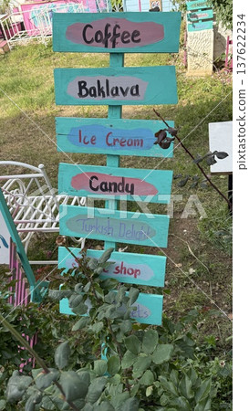 Colorful signpost in garden with directions to coffee, baklava, ice cream, and other treats Colorful signpost in garden with directions to coffee, baklava, ice cream, and other treats 137622234
