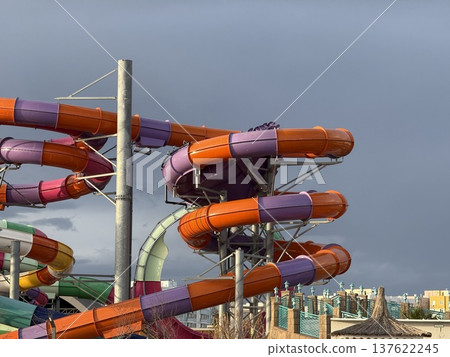 Water park with colorful spiral slides against grey sky, ideal for summer leisure background 137622245