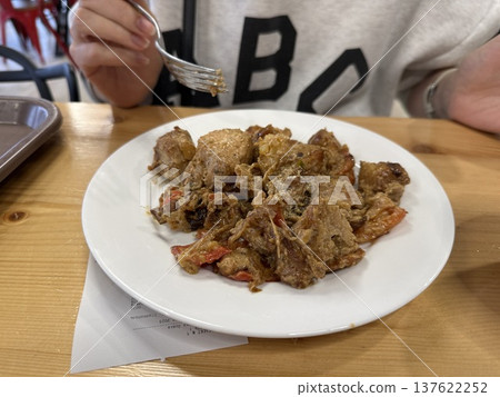 Person eating shawarma on a white plate at a wooden table Person eating shawarma on a white plate at a wooden table 137622252
