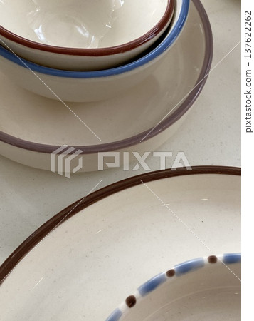 Ceramic dishes with blue and brown rim designs arranged on neutral background Ceramic dishes with blue and brown rim designs arranged on neutral background 137622262